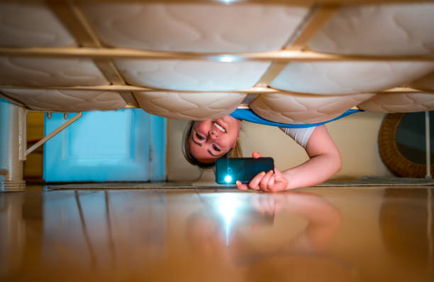 istock Woman with a flashlight looking under the bed 1310640203