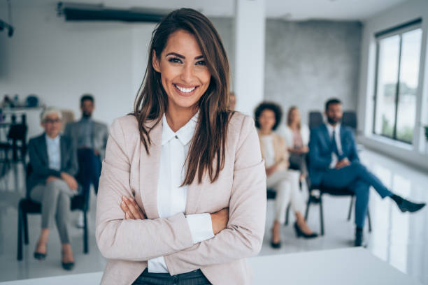 smiling public speaker in front of her colleagues in conference hall. - business conference meeting teamwork imagens e fotografias de stock