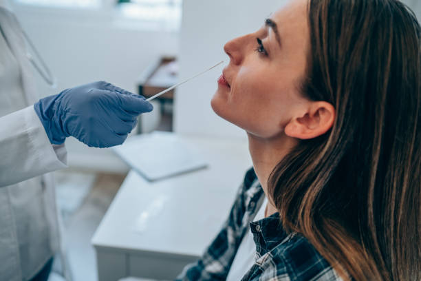 joven haciéndose la prueba de coronavirus/covid-19 en clínica médica. - bastoncillo de algodón fotografías e imágenes de stock