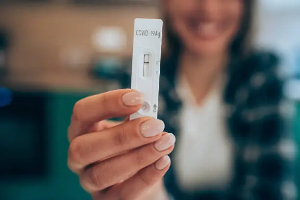 Close-up shot of woman's hand holding a negative test device. Happy young woman showing her negative Coronavirus/Covid-19 rapid test. Focus is on the test.