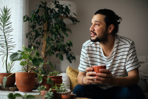 Man holding coffee cup while looking away at home