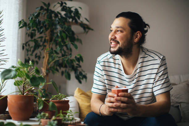 istock Man holding coffee cup while looking away at home 1310650466