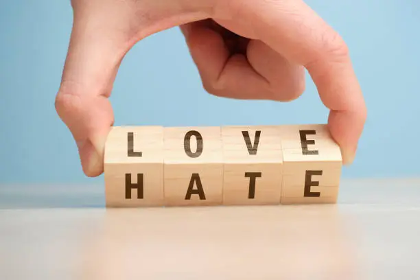 Photo of The concept of choosing between love and hate on wooden cubes is turned over by hand.