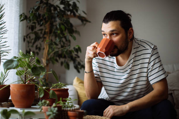 istock Man holding coffee cup while looking away at home 1310650570