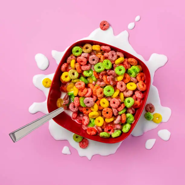 Photo of Bowl of colorful fruit loops with spilled milk around the bottom