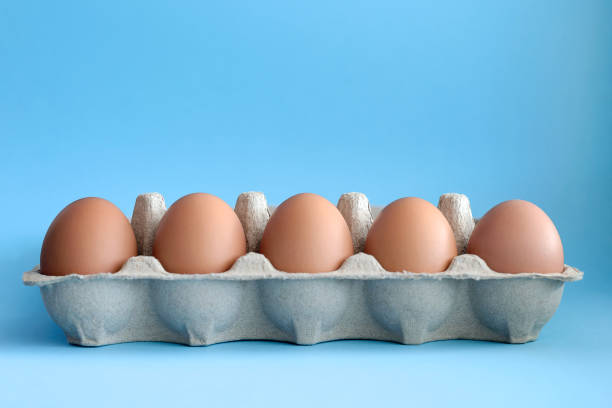 istock Nine brown eggs in a paper tray on the light blue table. Concept 1310651937