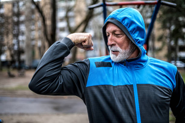 senior männlichen bodybuilder flexing seinen bizeps. - flexing muscles stock-fotos und bilder