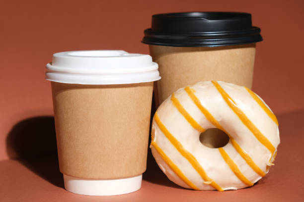 istock Hot drinks paper containers and donut on brown background 1310655259