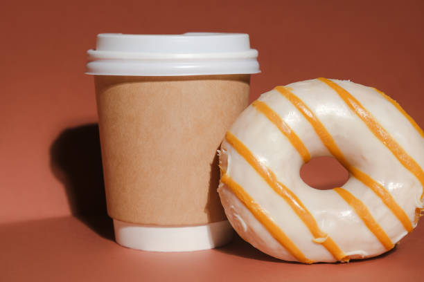 istock Take away coffee container and sweet glazed doughnut on brown background 1310655330