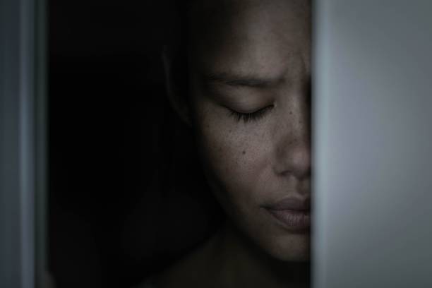 istock A sad afraid woman hiding in a dark closet alone at home. 1310658108