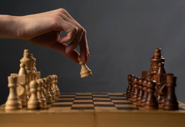 Hand moving white pawn and making first step Hand moving white pawn and making first step. chess board photos stock pictures, royalty-free photos & images