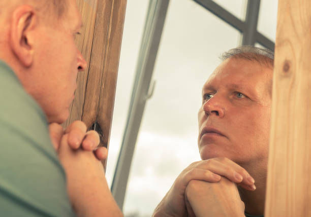 istock Middle-aged man looking at mirror reflection seriously, thinking about his age and life 1310674505