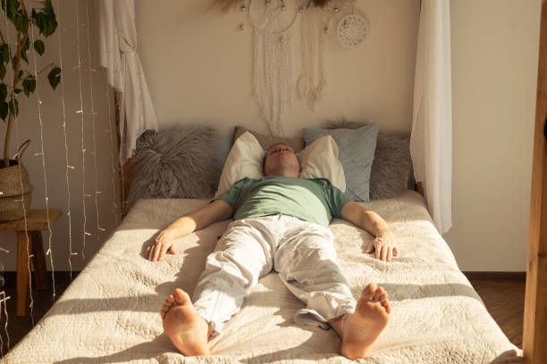Lazy man sleeping or dreaming on daytime with daylight on bed in bedroom.