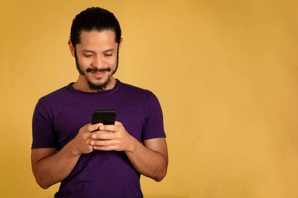 istock Young man portrait using smartphone with yellow background 1310678405