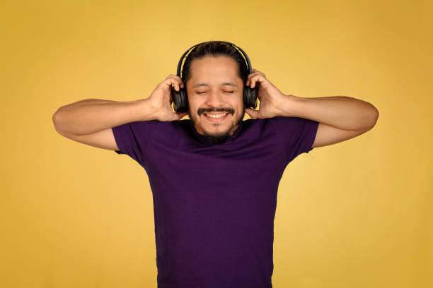 молодой человек портрет с желтым фоном - men smiling headphones individuality стоковые фото и изображения