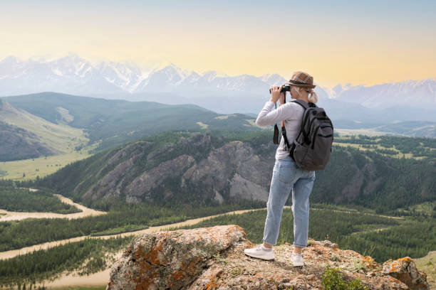 istock Hiker with backpack looking in binoculars on top of mountains at sunset. 1310679283