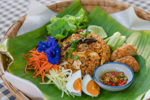 istock Delicious tom yum fried rice with prawns with salted egg , Fried chicken , top with mango vegetable side dishes Butterfly pea and Chilli Fish Sauce on banana leaf in basket. Thai food style. 1310692570