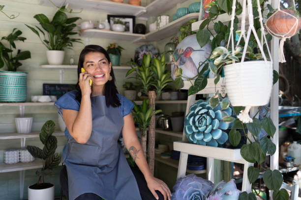istock Young woman smiling using mobile phone in her garden shop 1310693846