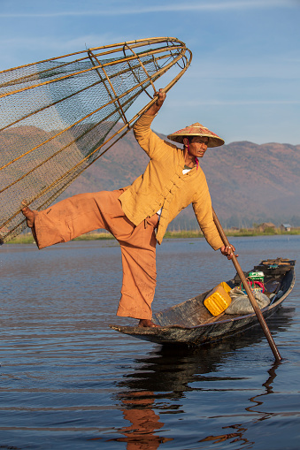 Inle lake, Myanmar, Burma - jan 14, 2016 : Burmese fisherman on bamboo boat catching fish in traditional way with handmade net. Inle lake, Myanmar, Burma