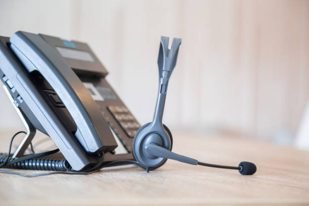 istock Communication support, call center and customer service help desk. VOIP headset on telephone keyboard. 1310702356
