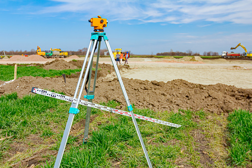 Zrenjanin, Vojvodina, Serbia - March 30, 2018: Surveyor instrument and leveling lath are used for measuring level on construction site. Surveyors ensure precise measurements before undertaking large construction projects.