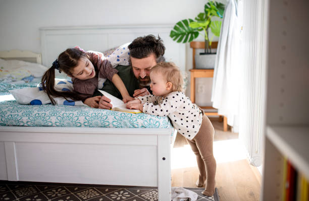 istock Father with two small daughters having fun on bed at home. 1310709389