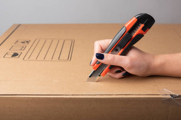 istock Female hand cutting with utility knife carton box 1310709449