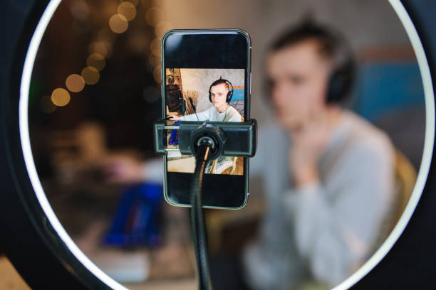 istock Man recording video on smartphone during the work at home on computer. Young guy recording on professional microphone speash about music. Phone in focus 1310709609