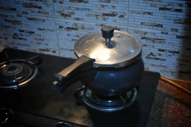 High pressure aluminum cooking pot with safety cover an image isolated on stove,india.