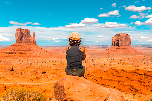 A young girl with black t-shirt sitting in the center of the photo on a stone in the Monument Valley National Park in the visitor center. Utah\