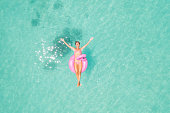 Drone view of woman floating on inflatable flamingo