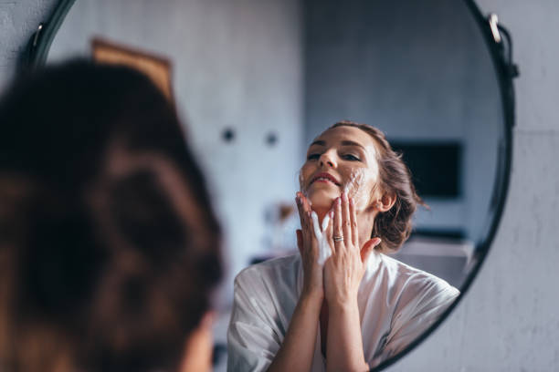 woman in the bathroom washing her face with foam - massage creme imagens e fotografias de stock