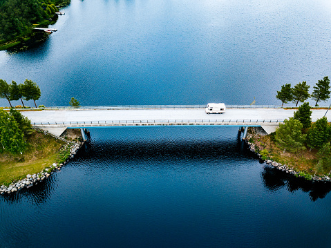 Aerial view Caravan trailer or Camper rv on the bridge over the lake in Finland. Summer holiday trip.