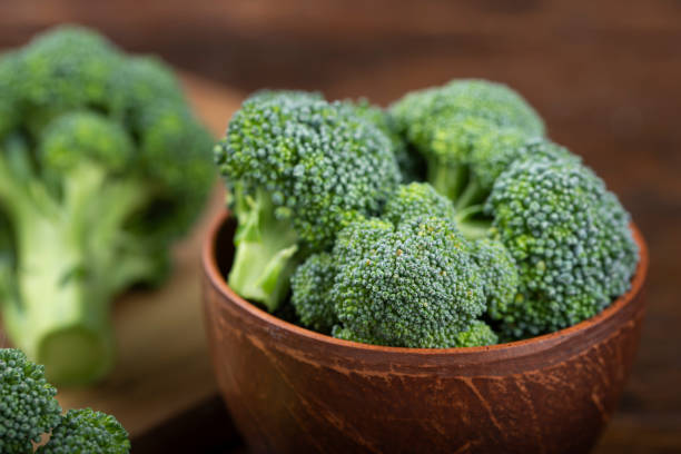 Bunch of fresh green broccoli on clay plate over Bunch of fresh green broccoli on clay plate over wooden background. broccoli crowns stock pictures, royalty-free photos & images