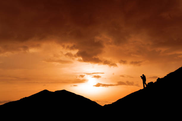 A photographer taking photo in silhouette against sunset time beautiful sky. A photographer taking photo in silhouette against sunset time beautiful sky. Sky is red color and cloudy. He is unrecognizable. He is taking photo mountain  in Blacksea area in Turkey. muslim photographer stock pictures, royalty-free photos & images