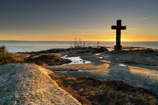Catholic cross towering over the fjord, golden hour