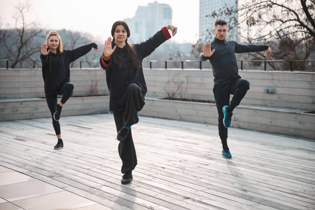 istock Practitioners of tai chi balancing on one leg on roof 1310727343