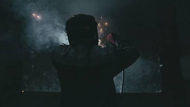 istock Forge workshop. Smithy. Worker in a welding hood helmet welds a part by electric welding. Sparks are reflected in the protective screen. 1310728192