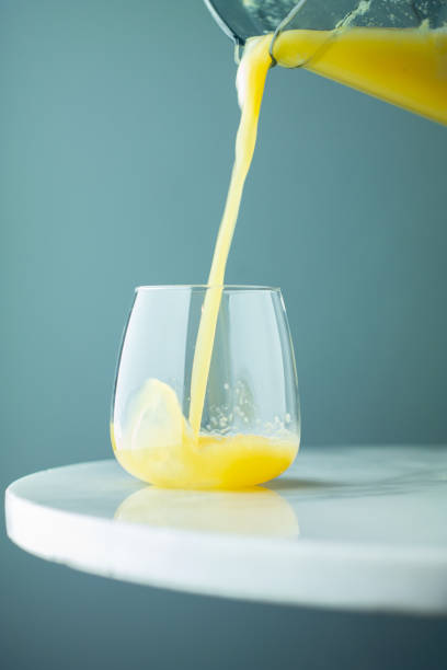 стакан свежего апельсинового сока с пеной, выливающейся из кувшина - smoothie fruit orange juice стоковые фото и изображения