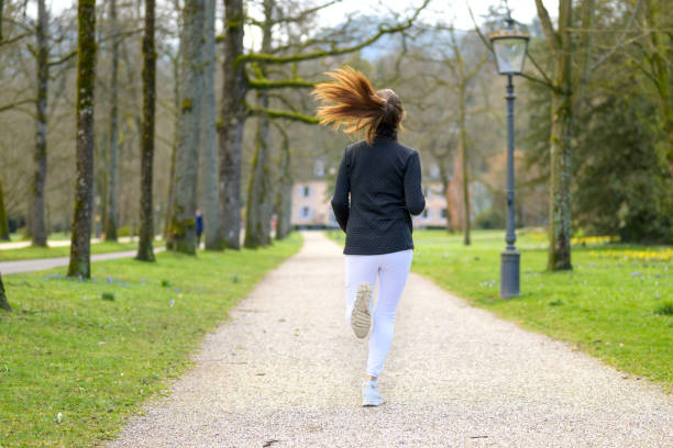 istock Fit woman jogging through a wooded park in spring 1310733743