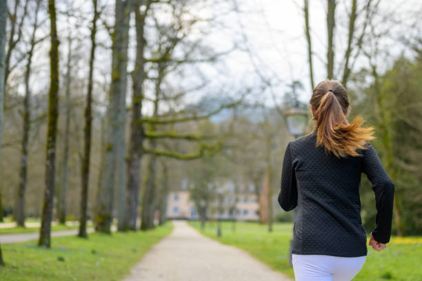 istock Fit woman jogging through a wooded park in spring 1310734014