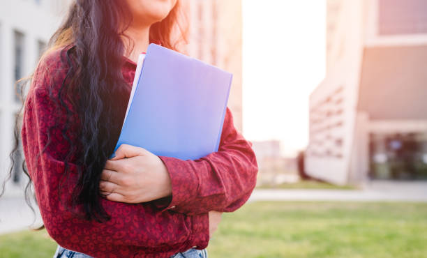 istock Close-up of a university student holding folders while standing outdoors at the college campus 1310735835