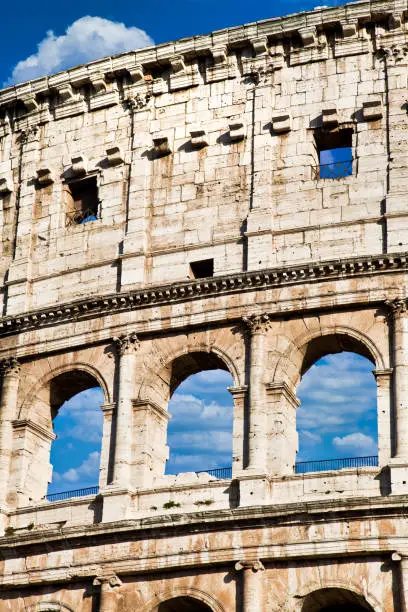 Rome, Italy. Arches archictecture of Colosseum (Colosseo) exterior with blue sky background and clouds.