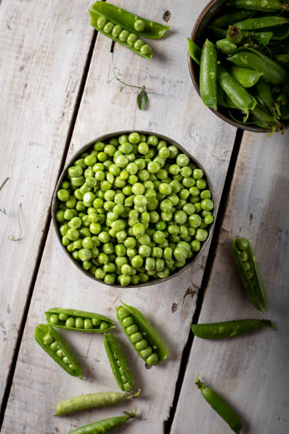 istock Fresh green peas in bowl on wooden background. 1310738044