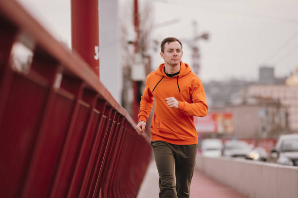 istock Man in orange hoodie running fast on a bridge 1310741238