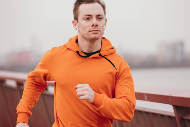 istock Man running fast on a bridge listening music in wireless earbuds 1310741977