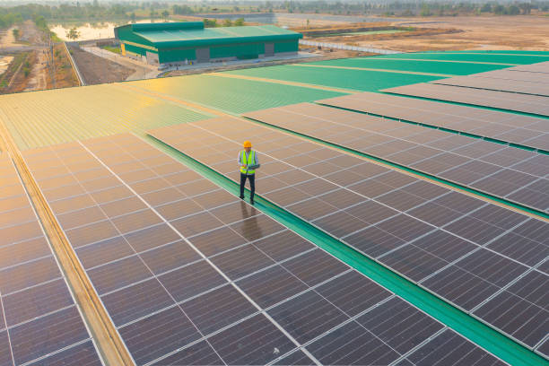 Aerial top view of engineer man or worker,people, with solar panels or solar cells on the roof in factory industry. Power plant, renewable energy source. Eco technology for electric power. Maintenance stock photo