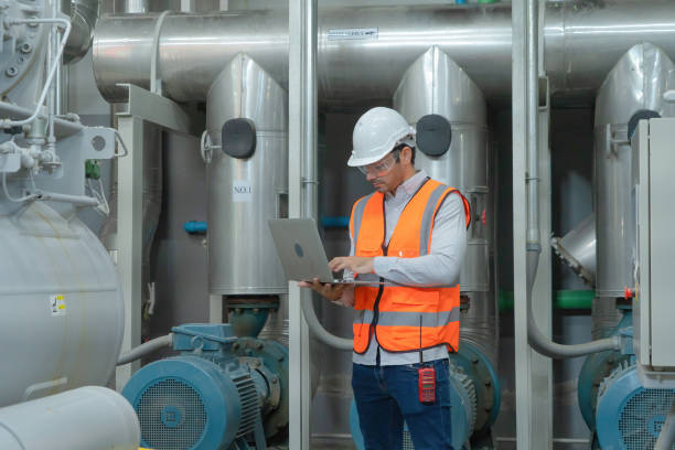 istock An engineer man or worker, people using a laptop computer, working in industry factory. Chiller tower or cooling tower in building. System work machine. Condenser Water Supply pipe lines. Ventilation. 1310743499