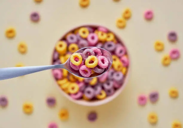 Photo of Colorful cereal loops in a bowl on a light background.