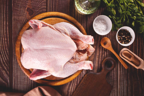 Whole raw chicken on a wooden table stock photo